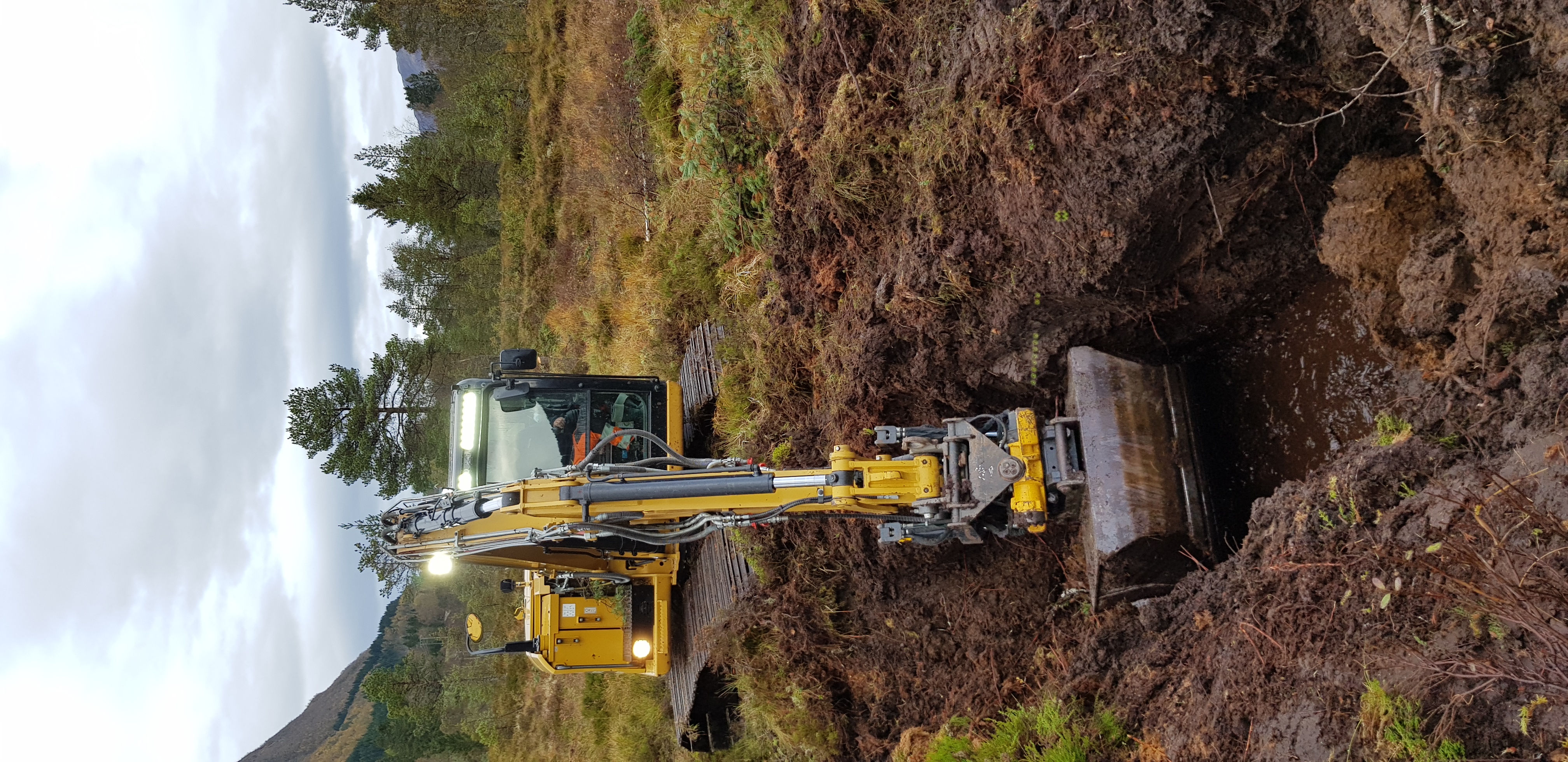 Gravemaskin lagar demning for å avskjære lekkasje av vatn frå høgmyra.